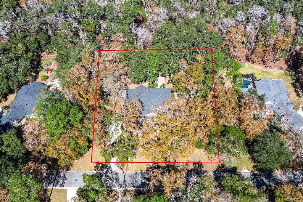 An aerial view shows a house nestled within a wooded lot outlined in red — 10320 SW 17TH PLACE, GAINESVILLE, FL