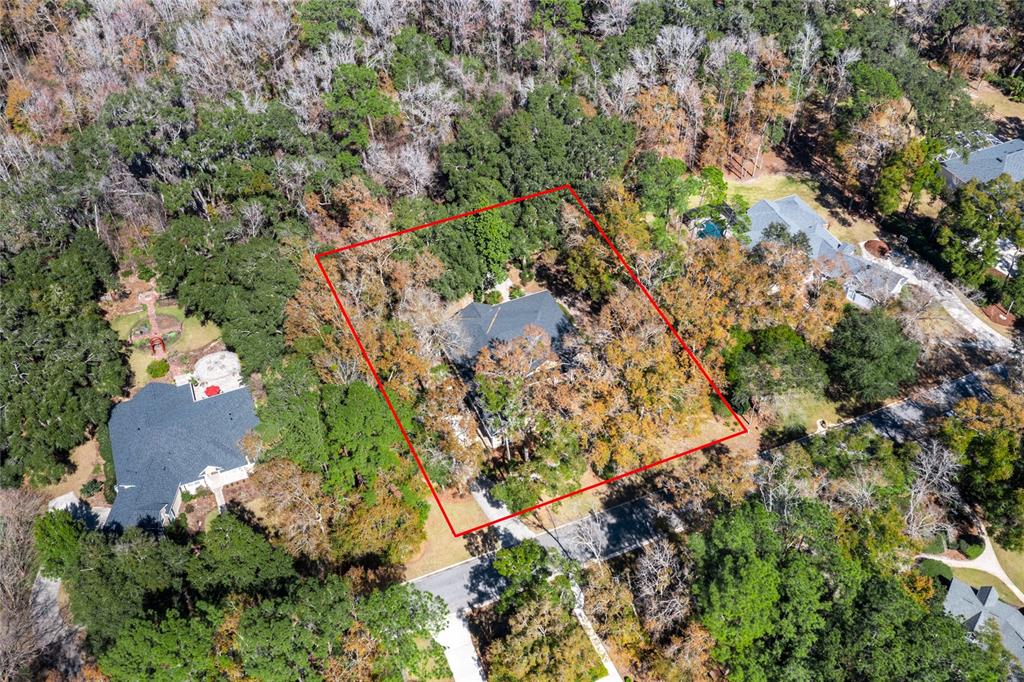An aerial view shows a house nestled within a wooded lot outlined in red — 10320 SW 17TH PLACE, GAINESVILLE, FL