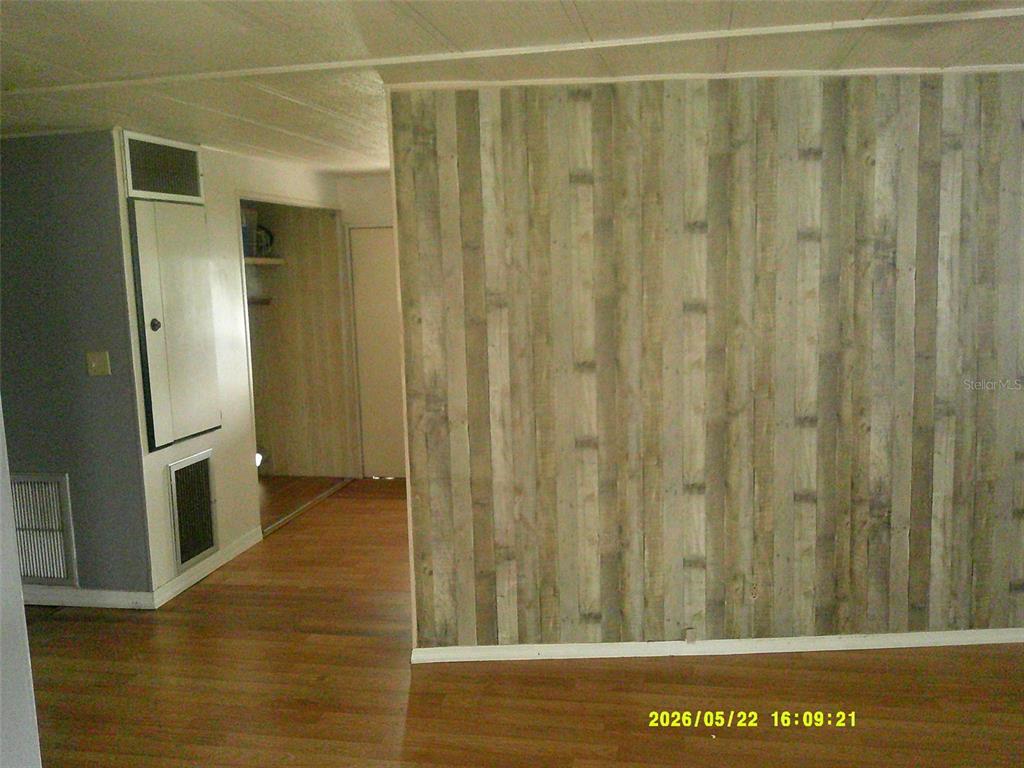A room features a wood-paneled accent wall, light wood flooring, and a white utility closet — 15211 SE 104TH COURT, SUMMERFIELD, FL
