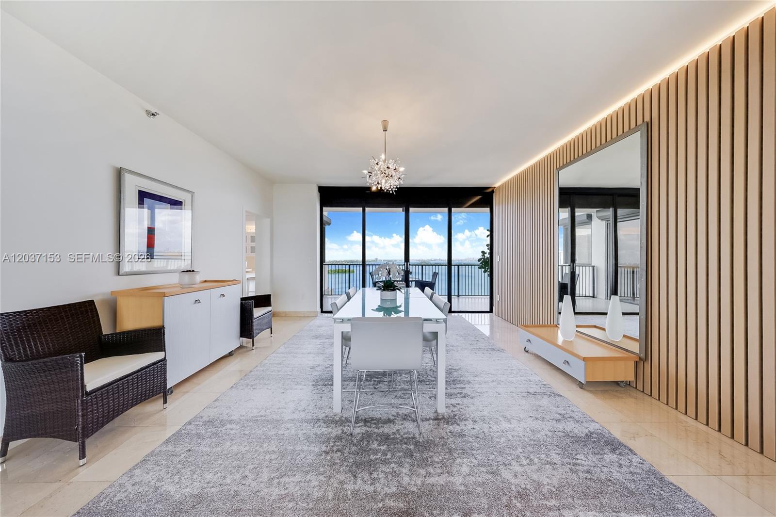 A dining room features a glass table, a large area rug, and a wood-slatted wall — 1000 Venetian Way # 1902, Miami FL 33139, MIAMI, FL