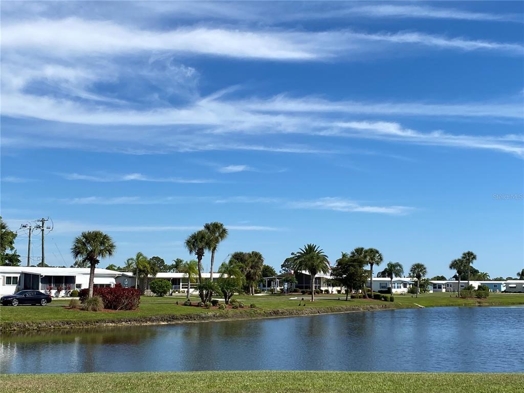 A pond sits in front of a row of mobile homes and palm trees — 248 EL PRADO, NORTH PORT, FL
