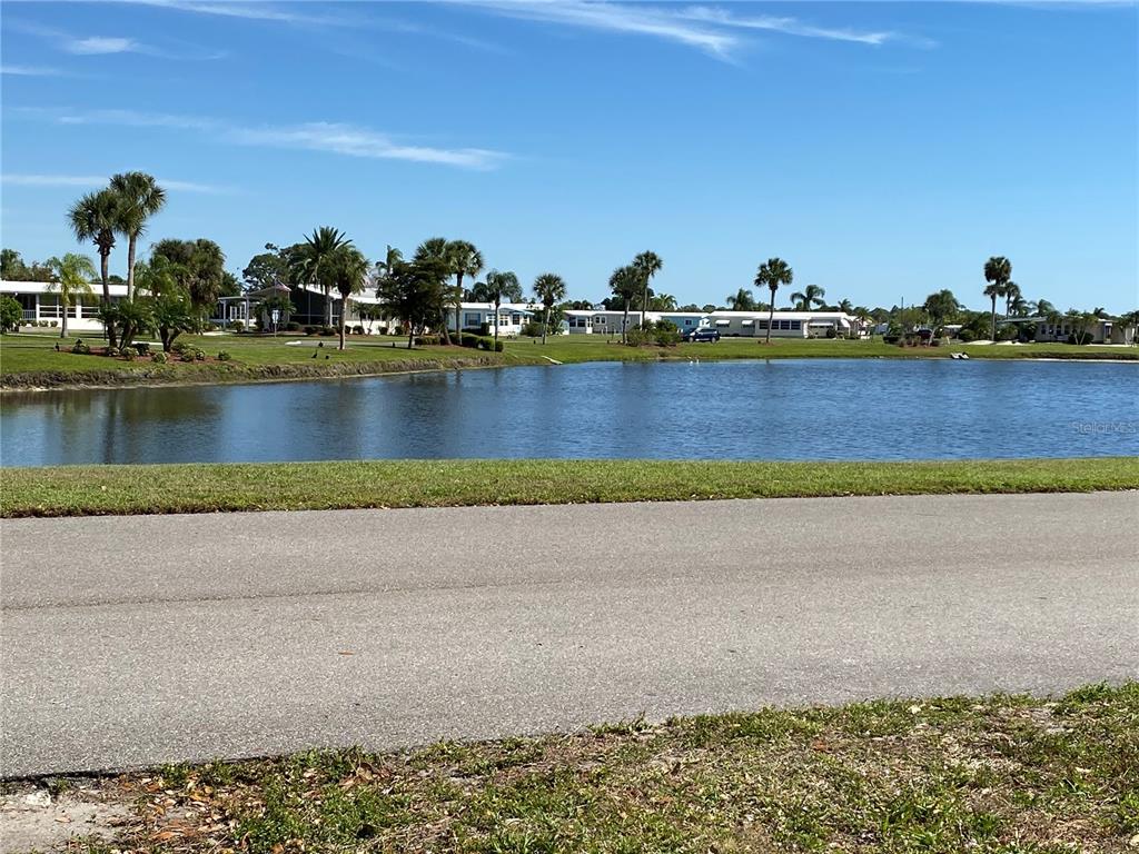 A view of a pond with palm trees and houses in the background — 248 EL PRADO, NORTH PORT, FL