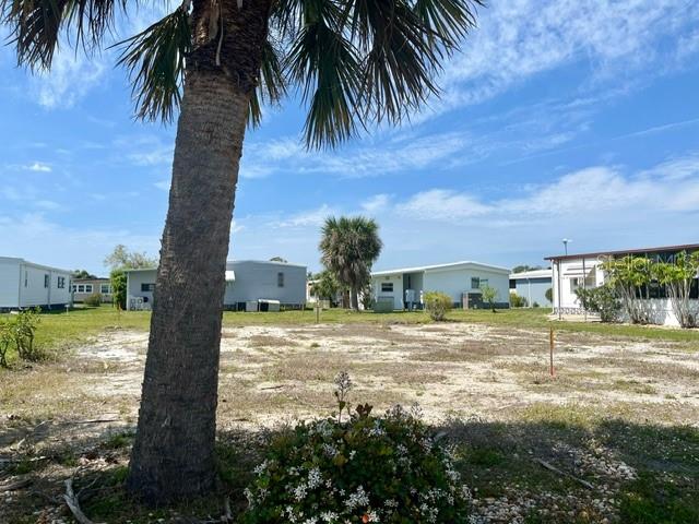 A vacant lot with a palm tree and surrounding mobile homes under a blue sky — 248 EL PRADO, NORTH PORT, FL