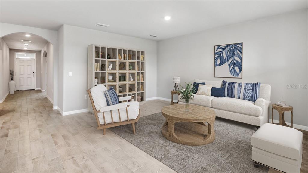 A living room features a bookshelf, white sofa, wooden coffee table, and light tile flooring — 26221 CORAL LAKES DRIVE, PUNTA GORDA, FL