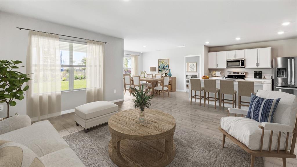 An open-concept living and dining area features a kitchen with white cabinets and stainless appliances — 26221 CORAL LAKES DRIVE, PUNTA GORDA, FL