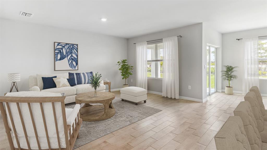 A bright living room features light tile floors, a white sofa, and a wooden coffee table — 26221 CORAL LAKES DRIVE, PUNTA GORDA, FL