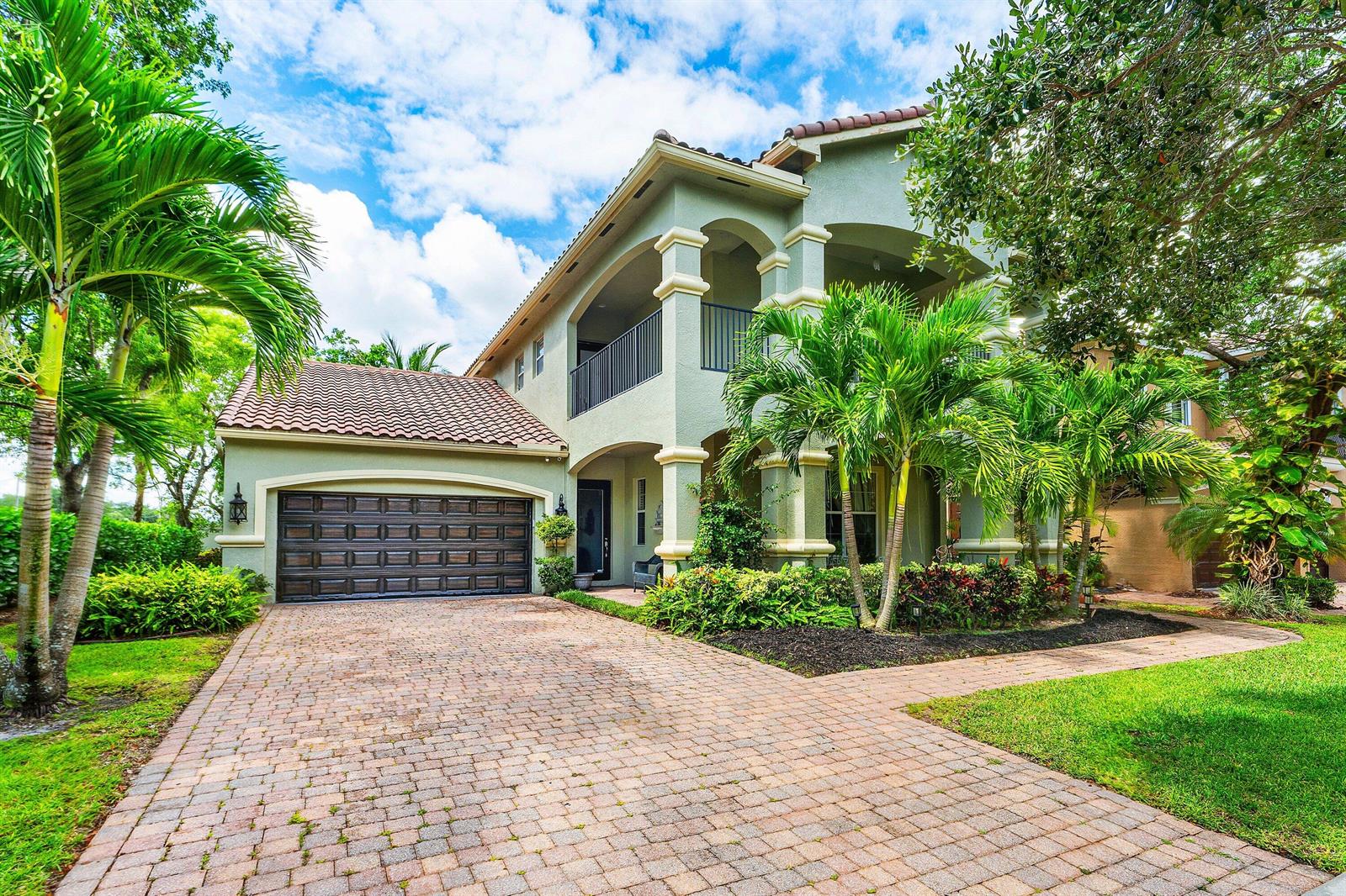 A two-story house with a tiled roof, arched balconies, and a brick paver driveway — 599 Cresta Circle, West Palm Beach FL 33413, WEST PALM BEACH, FL
