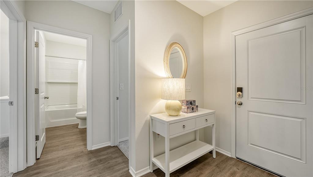 A white console table with a lamp and mirror sits in an entryway near a bathroom — 12919 RED DEER PLACE, PARRISH, FL