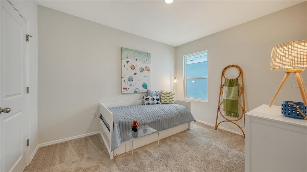 A bedroom features a white daybed, a small glass table, and a decorative rattan ladder — 12919 RED DEER PLACE, PARRISH, FL