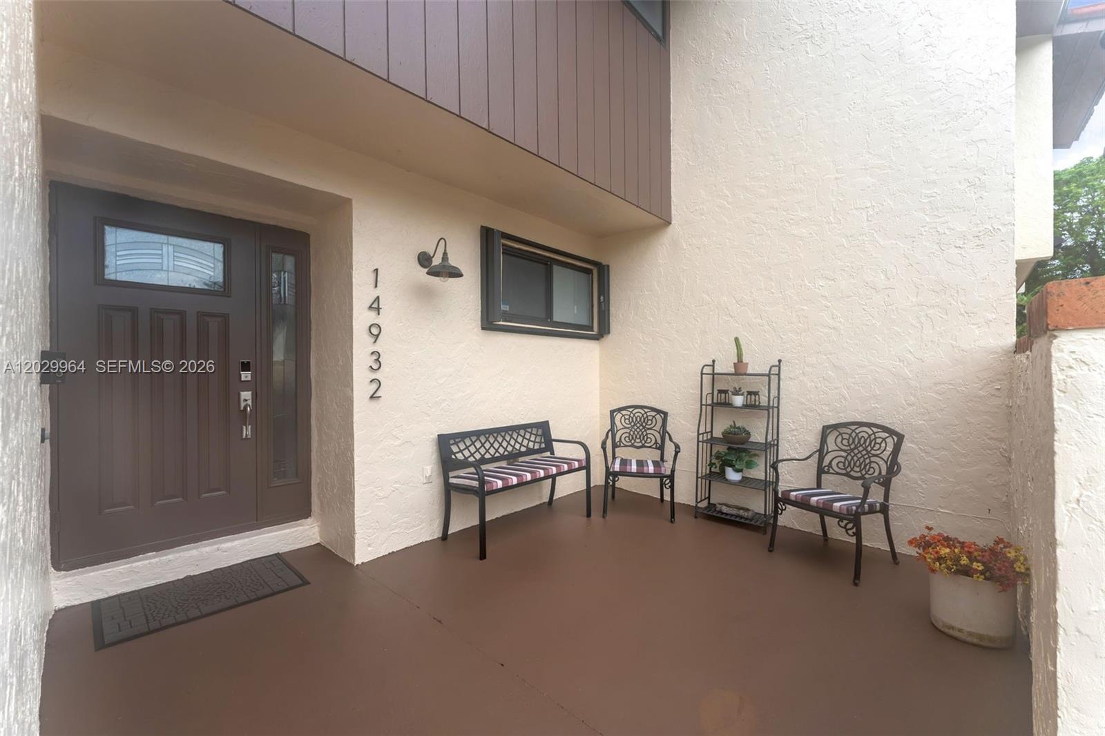 A covered patio features a brown door, metal furniture, and a small shelving unit — 14932 SW 89th St, Miami FL 33196, MIAMI, FL