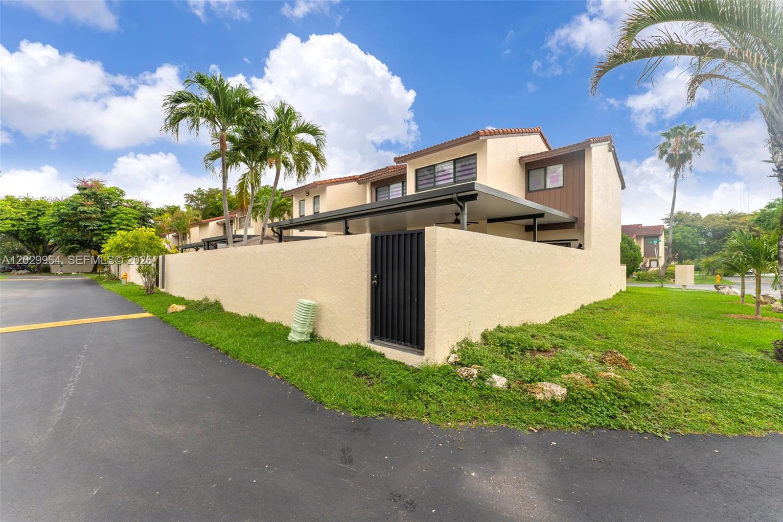 A tan two-story townhouse features a walled courtyard, a black gate, and palm trees — 14932 SW 89th St, Miami FL 33196, MIAMI, FL