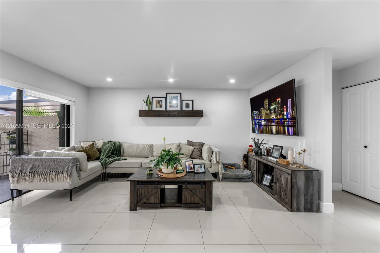 A living room features a sectional sofa, a wooden coffee table, and a wall-mounted television — 14932 SW 89th St, Miami FL 33196, MIAMI, FL