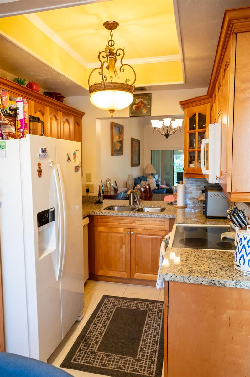 A kitchen with light wood cabinets, granite countertops, a white refrigerator, and a recessed ceiling — 7551 CAESAR Street # C, Lake Worth FL 33467, LAKE WORTH, FL