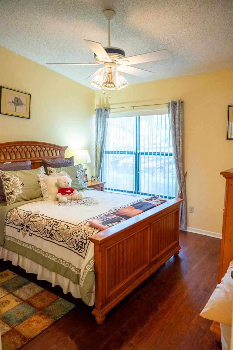 A bedroom features a wooden bed frame, a ceiling fan, and a window with curtains — 7551 CAESAR Street # C, Lake Worth FL 33467, LAKE WORTH, FL