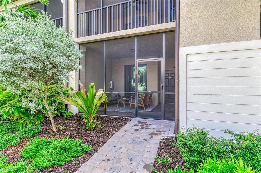 A paved walkway leads to the screened-in patio of a multi-story residential building — 5685 PALMER CIRCLE UNIT 105, BRADENTON, FL