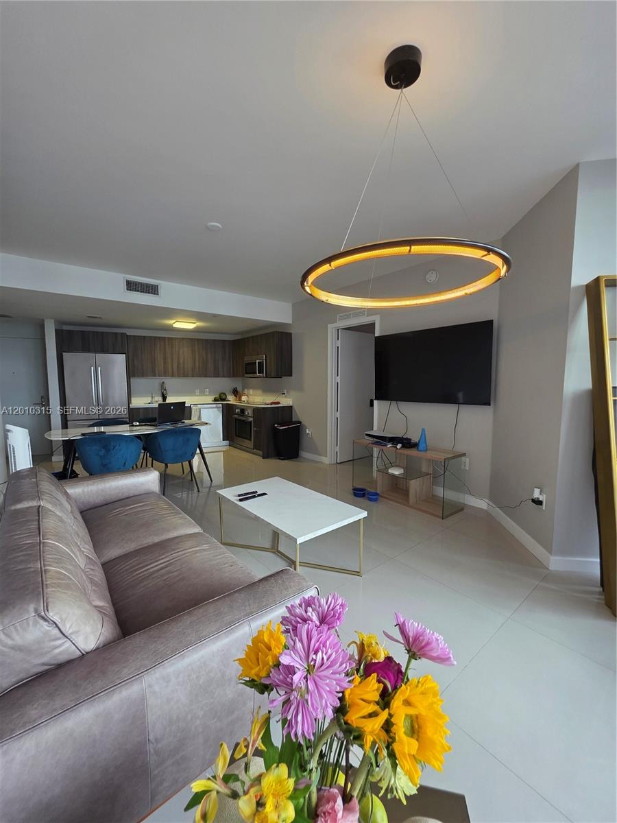 A living room with a leather sofa, white coffee table, and open-concept kitchen — 488 NE 18th St # 301, Miami FL 33132, MIAMI, FL