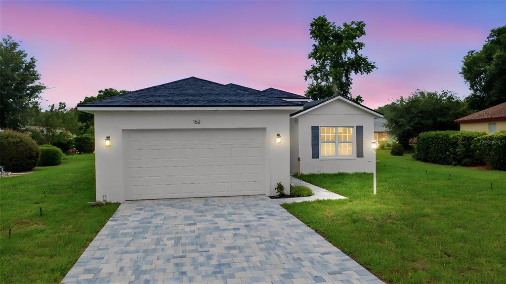 A single-story house with a white exterior, a two-car garage, and a paved driveway — 162 W ROMANY LOOP, BEVERLY HILLS, FL