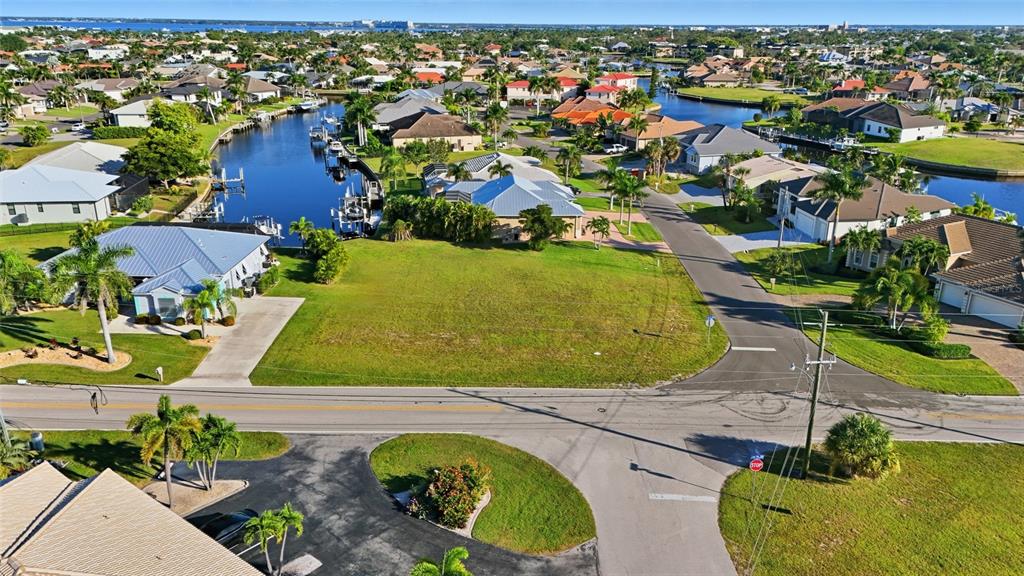 An aerial view shows a vacant residential lot situated between houses and a canal — 600 VIA TRIPOLI, PUNTA GORDA, FL