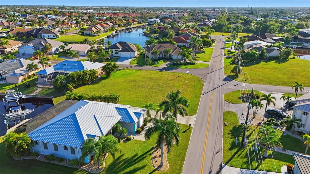 An aerial view of a residential neighborhood featuring houses, a canal, and a paved road — 600 VIA TRIPOLI, PUNTA GORDA, FL