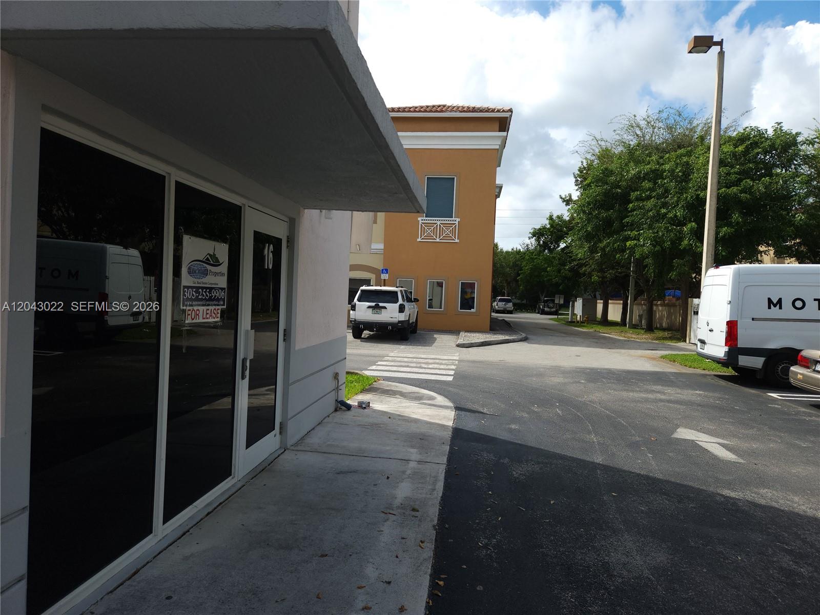An exterior view of a commercial building entrance with a for lease sign and parking — 13331 SW 132 AVE # 16, Miami FL 33186, MIAMI, FL