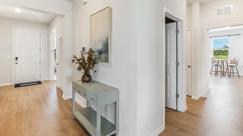 A light-filled entryway features wood-look flooring, a console table, and a view into a dining area — 10433 WOODLAND GARDEN WAY, PARRISH, FL