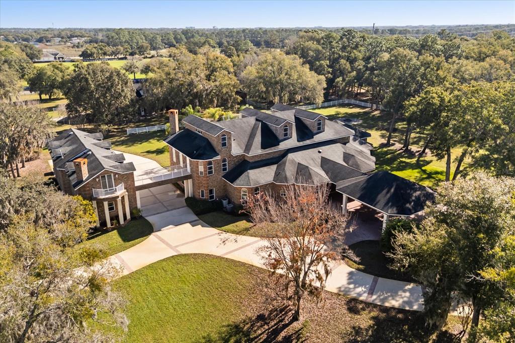 An aerial view shows a large brick house with a bridge connecting two building sections — 1501 LAKE MARKHAM ROAD, SANFORD, FL