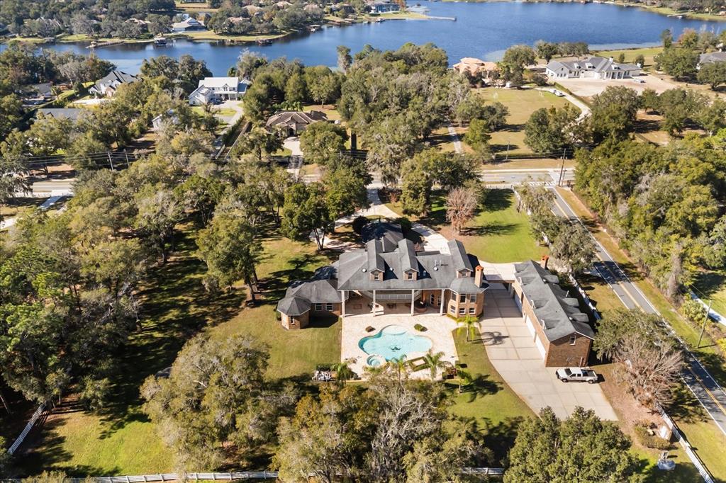 An aerial view shows a large house with a pool, detached garage, and surrounding trees — 1501 LAKE MARKHAM ROAD, SANFORD, FL