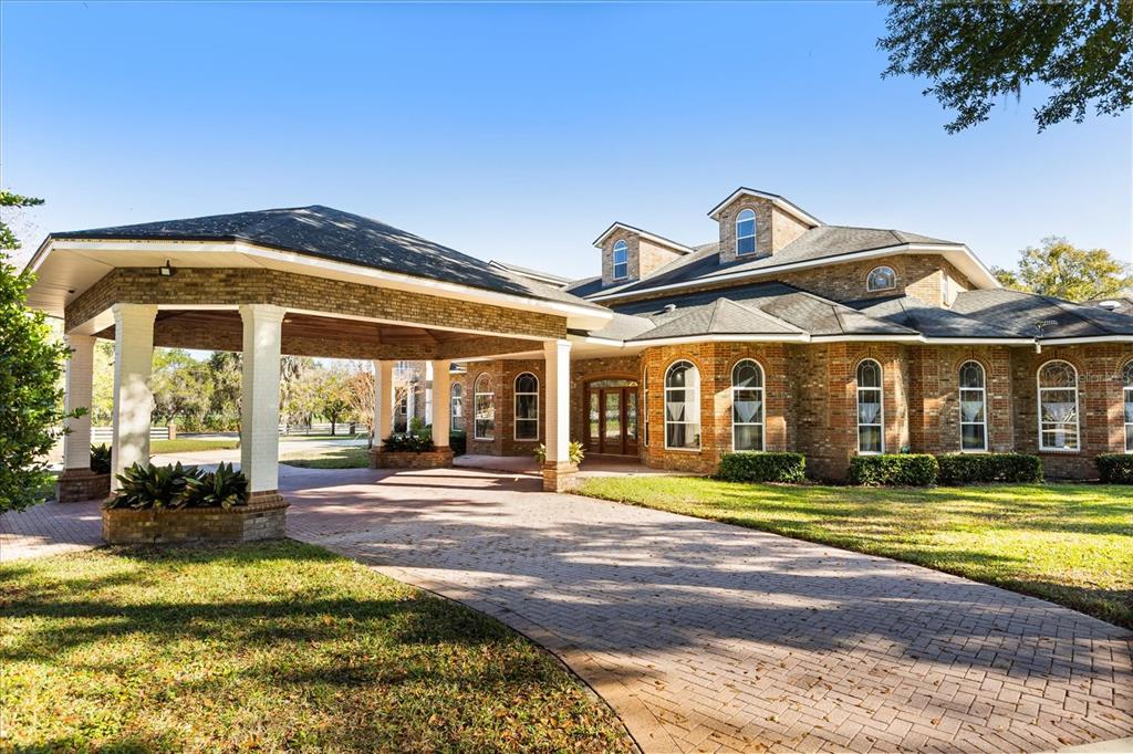 A brick house with a large porte-cochère and a paved driveway under a clear sky — 1501 LAKE MARKHAM ROAD, SANFORD, FL