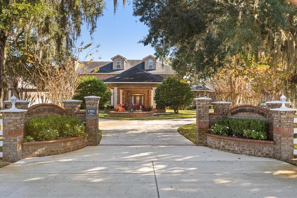 A brick gated entrance leads to a large house with a circular driveway and fountain — 1501 LAKE MARKHAM ROAD, SANFORD, FL