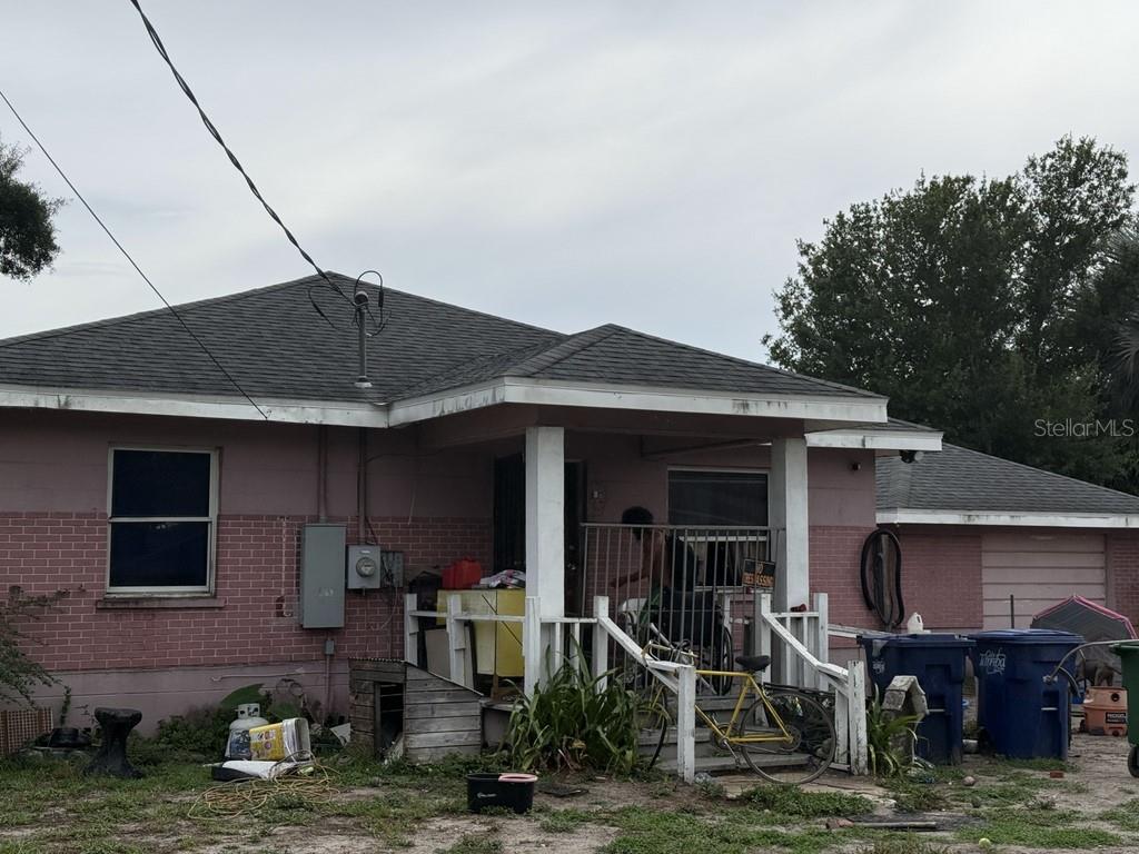 A single-story pink brick house with a front porch, a bicycle, and trash bins outside — 5207 E 20TH AVENUE, TAMPA, FL