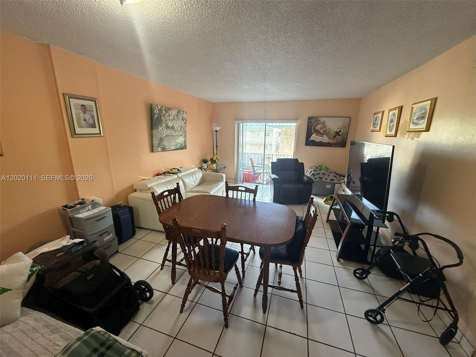 A living and dining room area features tiled floors, peach walls, and a sliding glass door — 6780 W 2nd Ct # 313, Hialeah FL 33012, HIALEAH, FL