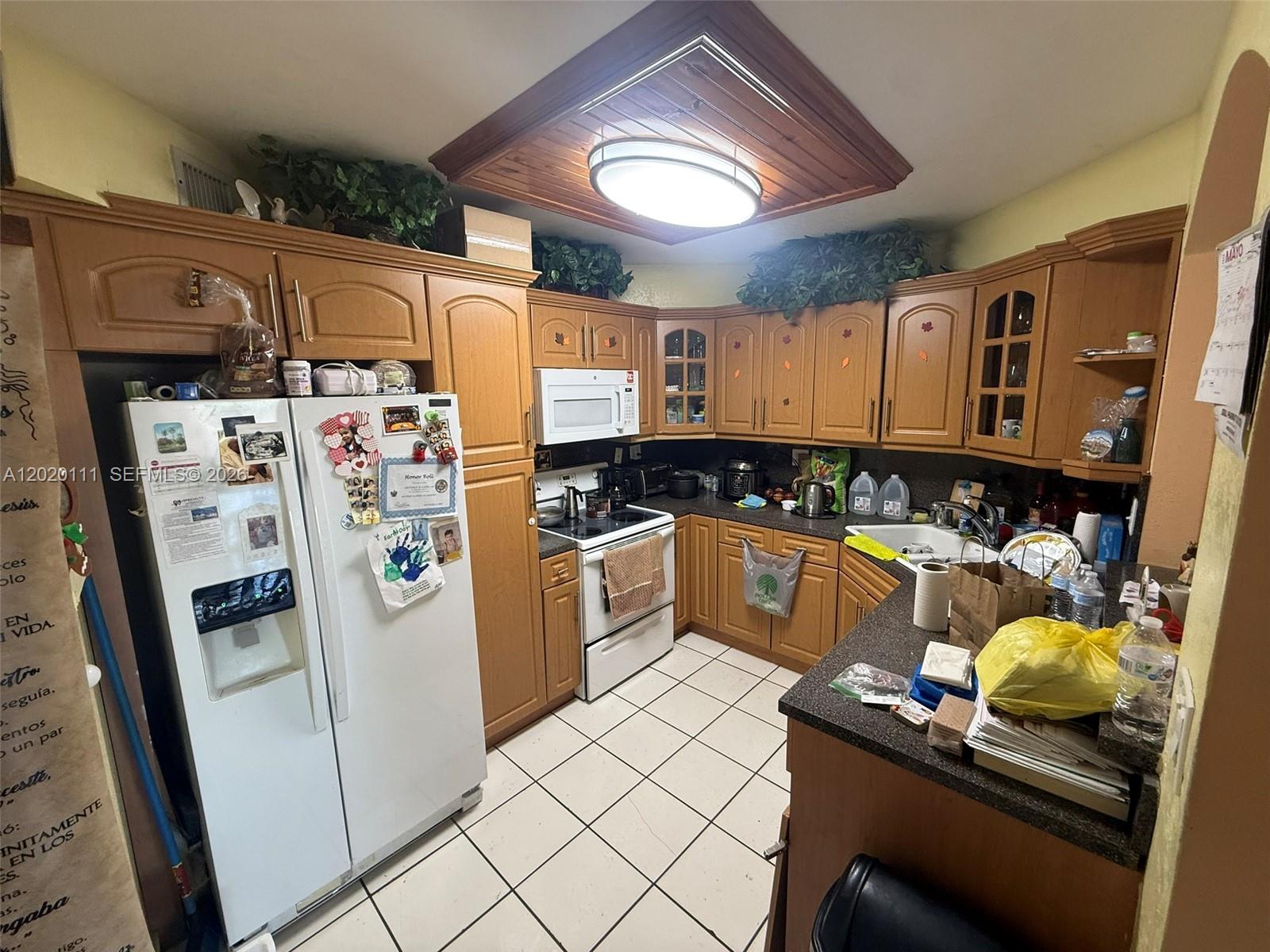 A kitchen features wood cabinets, white appliances, a tiled floor, and a central ceiling light — 6780 W 2nd Ct # 313, Hialeah FL 33012, HIALEAH, FL