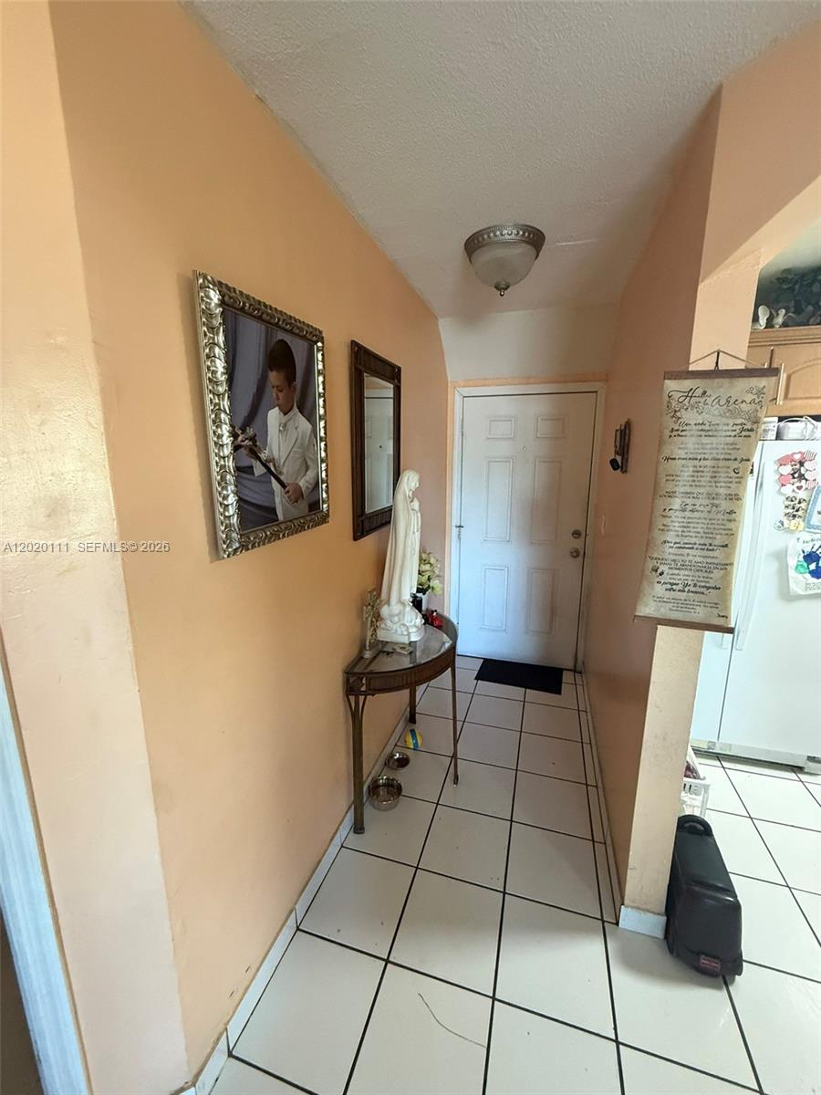 A tiled entryway features a console table with a religious statue and framed wall art — 6780 W 2nd Ct # 313, Hialeah FL 33012, HIALEAH, FL