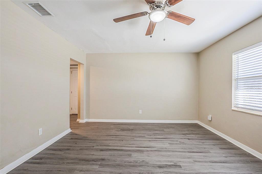 An empty room features light-colored walls, gray wood-look flooring, and a ceiling fan — 3645 6TH STREET S, ST PETERSBURG, FL