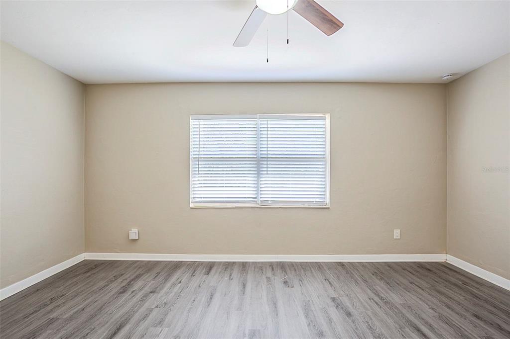 An empty bedroom features light beige walls, gray wood-look flooring, and a ceiling fan — 3645 6TH STREET S, ST PETERSBURG, FL