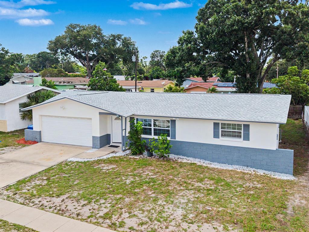 A single-story house with a white exterior, gray stone base, and a two-car garage — 1354 ROSERY ROAD NE, LARGO, FL