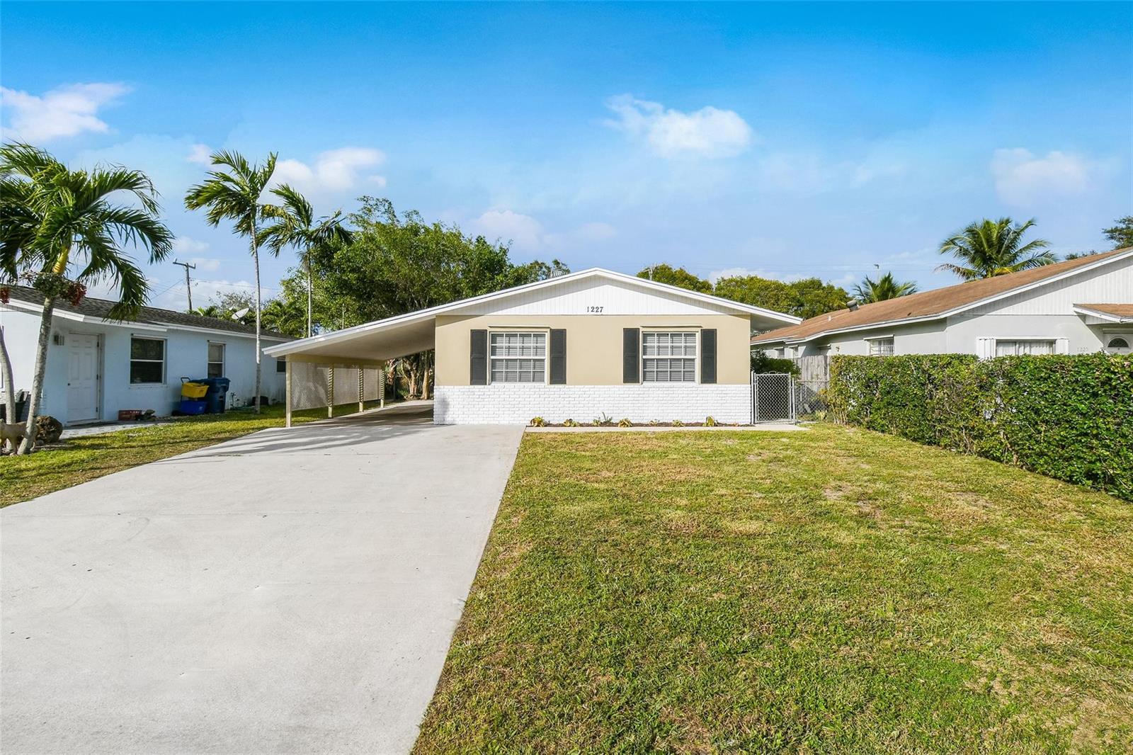 A single-story house with a white brick base, tan siding, and an attached carport — 1227 Cherokee Street, Jupiter FL 33458, JUPITER, FL
