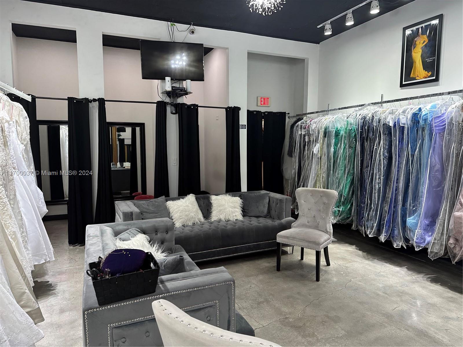 A clothing boutique features a gray tufted sofa, a matching chair, and racks of formal dresses — 14248 SW 8th St, Miami FL 33184, MIAMI, FL