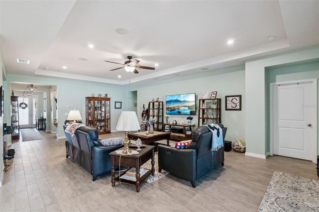 A spacious living room features light green walls, tile flooring, and a tray ceiling — 3904 REDFIN PLACE, KISSIMMEE, FL