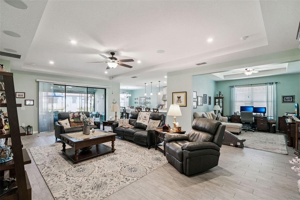An open-concept living room features tile flooring, a tray ceiling, and a home office area — 3904 REDFIN PLACE, KISSIMMEE, FL