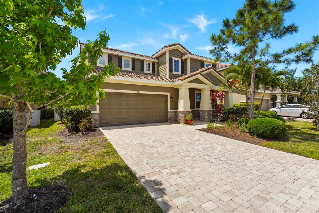 A two-story suburban house with a paved driveway, stone accents, and a two-car garage — 5309 CHARLIE BROWN LANE, SARASOTA, FL