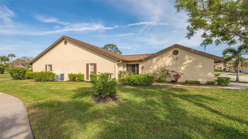 A tan, single-story residential building with a brown roof and a landscaped front yard — 5905 DORAL DRIVE, SARASOTA, FL