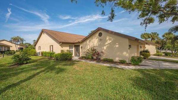 A tan, single-story residential building with a brown roof and a concrete driveway — 5905 DORAL DRIVE, SARASOTA, FL