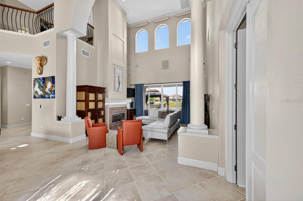 A two-story living room features tile floors, a fireplace, and large arched windows — 2234 CALLAWAY COURT, DAVENPORT, FL