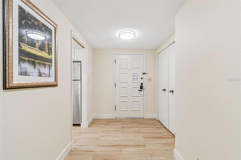 An entryway features light wood-look tile flooring, a white front door, and a closet — 36750 US HIGHWAY 19 UNIT 21202, PALM HARBOR, FL