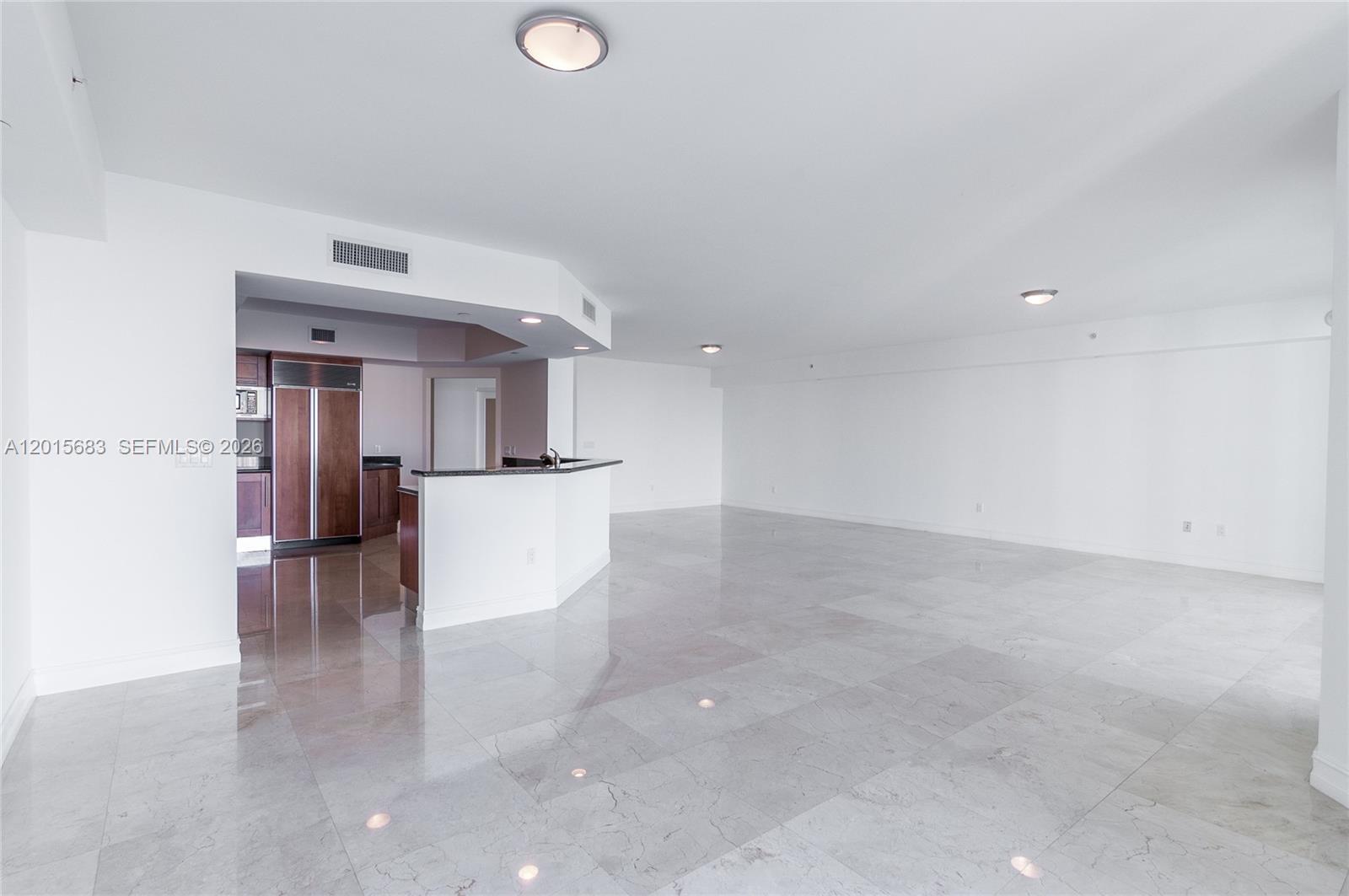 An open-concept living area features white walls, marble tile flooring, and a kitchen island — AVENTURA, FL