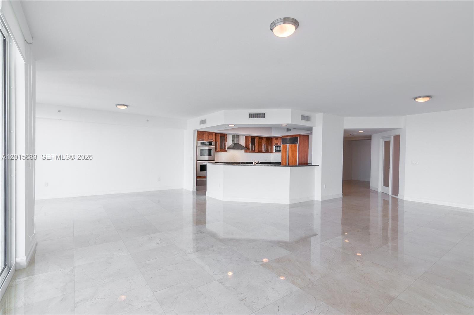 An open-concept living area features a kitchen with wood cabinets and polished tile floors — AVENTURA, FL