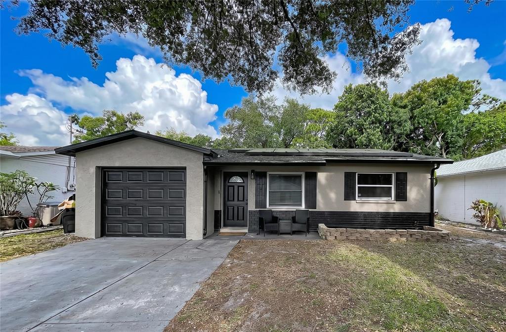 A single-story house with a gray stucco exterior, a black garage door, and a front porch — 8320 43RD WAY N, PINELLAS PARK, FL