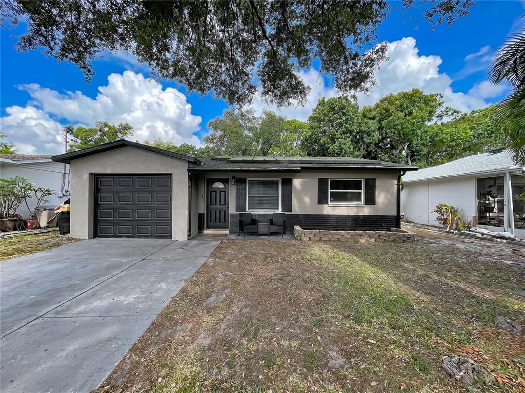 A single-story house with a gray exterior, black garage door, and a small front patio — 8320 43RD WAY N, PINELLAS PARK, FL