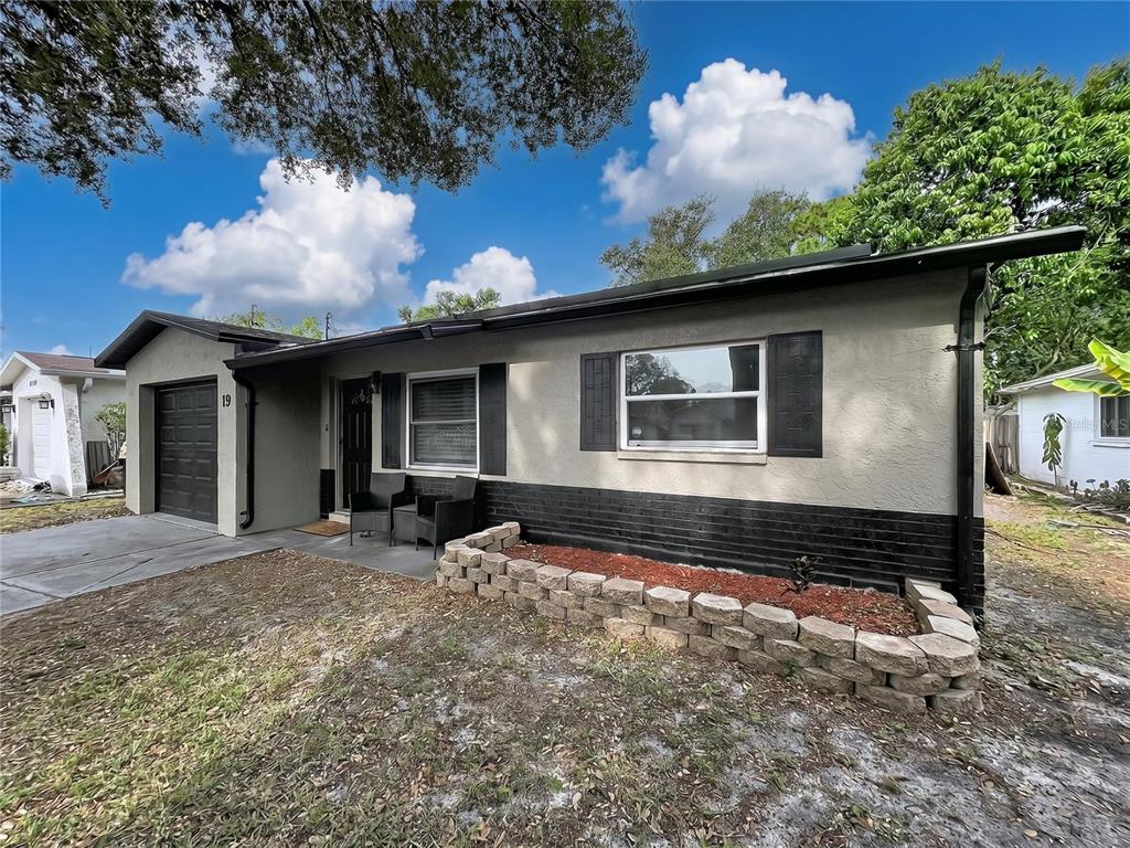 A single-story house with a gray stucco exterior, black accents, and a stone garden bed — 8320 43RD WAY N, PINELLAS PARK, FL